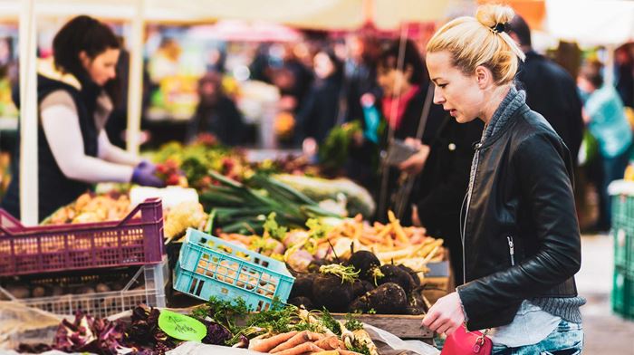 kvinde står og kigger på grøntsager på marked