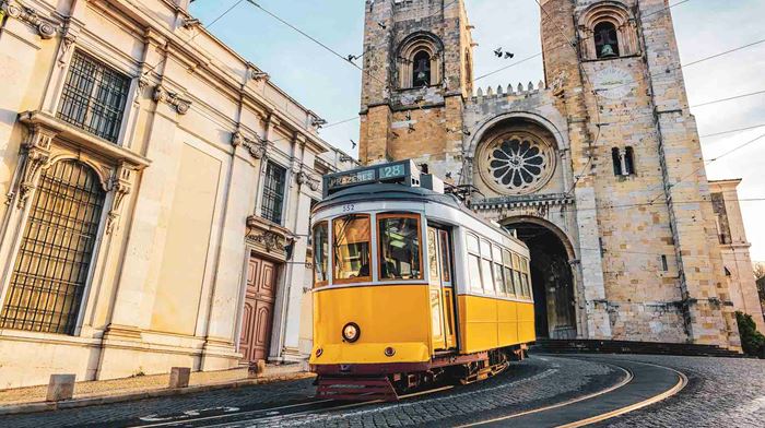 Portugal Lissabon en berømt gul sporvogn 28 passerer foran Santa Maria Katedralen