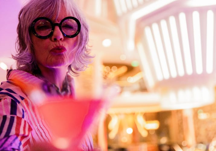 Kvinde med solbriller nyder drink i Celebrity Cruises martini bar med farvet stemningslys