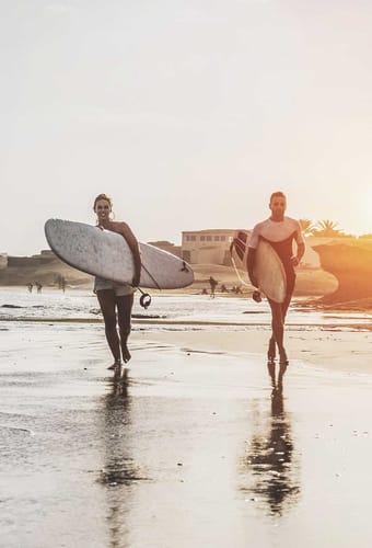 To surfere som går på stranden i Portugal