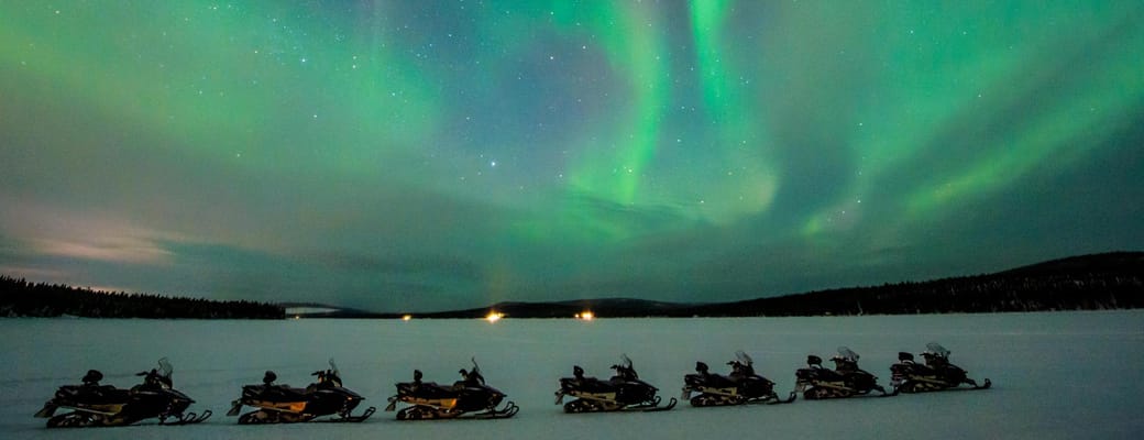 gr&oslash;nt nordlys over snescooterudflugte icehotel i svensk lapland