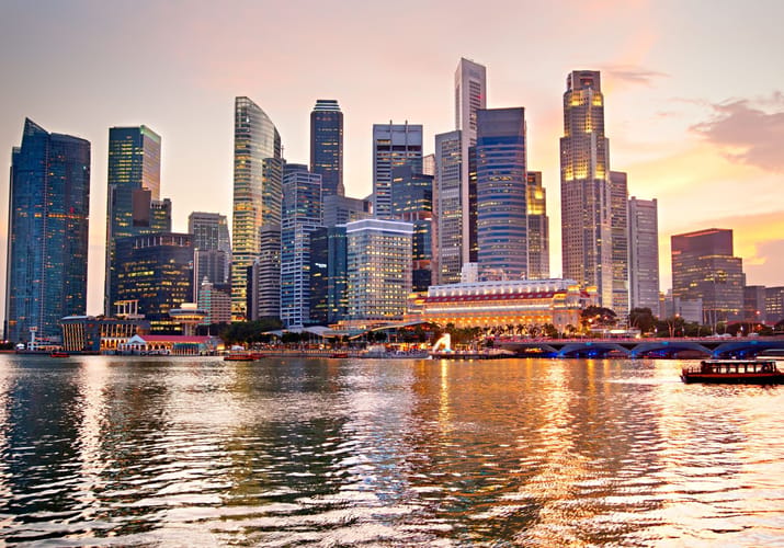 Singapore skyline ved Marina Bay i solnedgang med lys spejlet i havnen