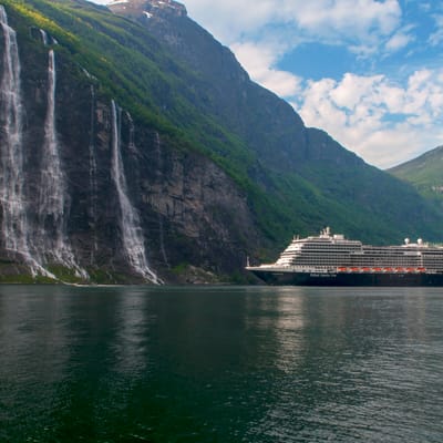 Holland America Line krydstogtskib sejler gennem spektakul&aelig;r norsk fjord med h&oslash;je klipper og vandfald