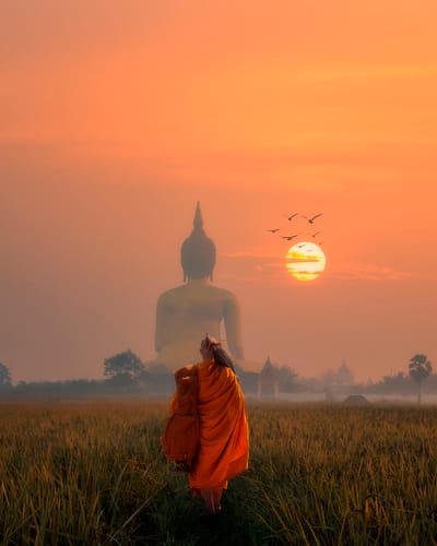 Munk går mod stor buddha figur i solnedgang i thailand