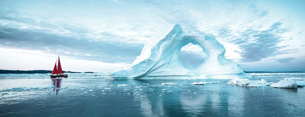 Gr&oslash;nland Ilulissat disko bugten baad med roedt sefl sejler ved isbjerg