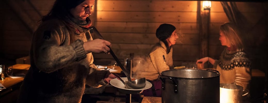 Camp Barentz: i dunkel belysning serverer kvinde suppe for 2 gæster
