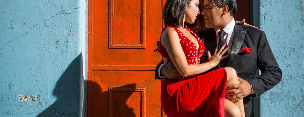 Tango-par i r&oslash;d kjole danser foran farverig husfacade i Buenos Aires