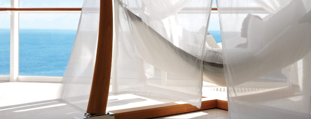 Luksuriøs hængehammock med hvide gardiner på Celebrity cruise skibets private poolområde med panoramaudsigt over det azurblå hav