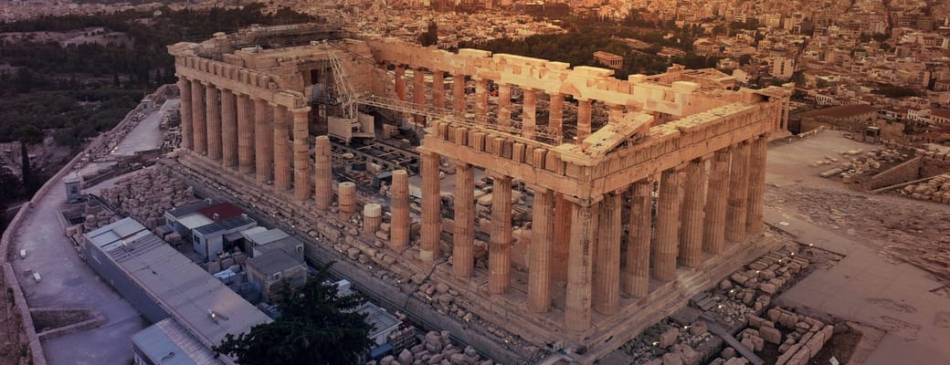 Akropolis og Parthenon i Athen set fra luften i solnedgang med storbyen bredt ud omkring