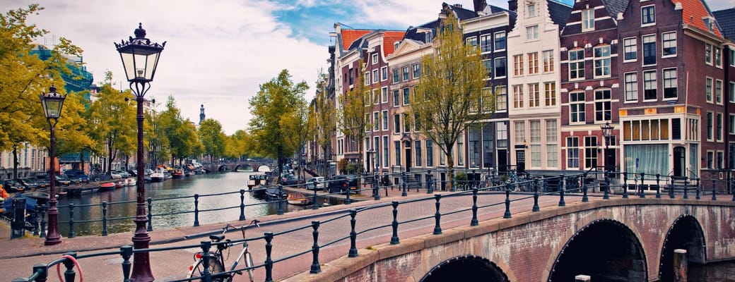 Bro over kanal med historiske huse i Amsterdam, Holland – krydstogtdestination