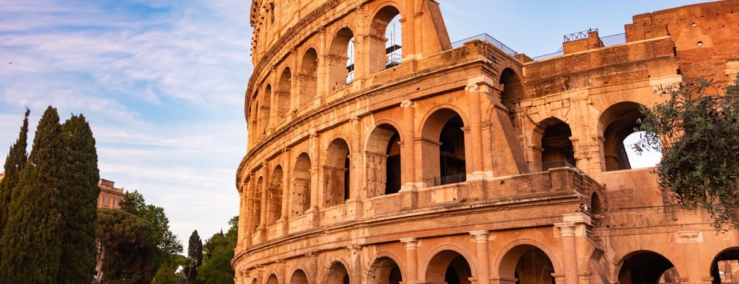 Colosseum i Rom badet i varmt aftenslys med blå himmel over