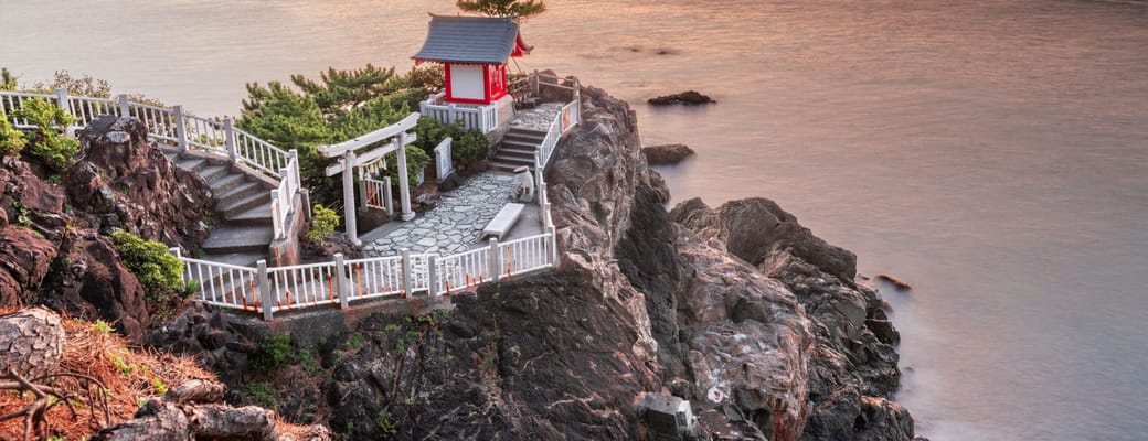 Watatsumi tempel p&aring; klippekysten i Kochi med r&oslash;dt torii-portanl&aelig;g og trapper ned til havet ved solnedgang