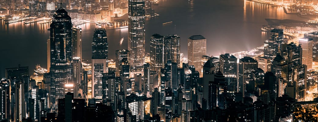 Hongkong skyline om natten med oplyste skyskrabere omkring Victoria Harbour