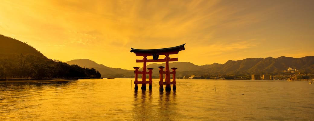 Den ber&oslash;mte r&oslash;de Torii-port ved Miyajima havn under gylden solnedgangshimmel