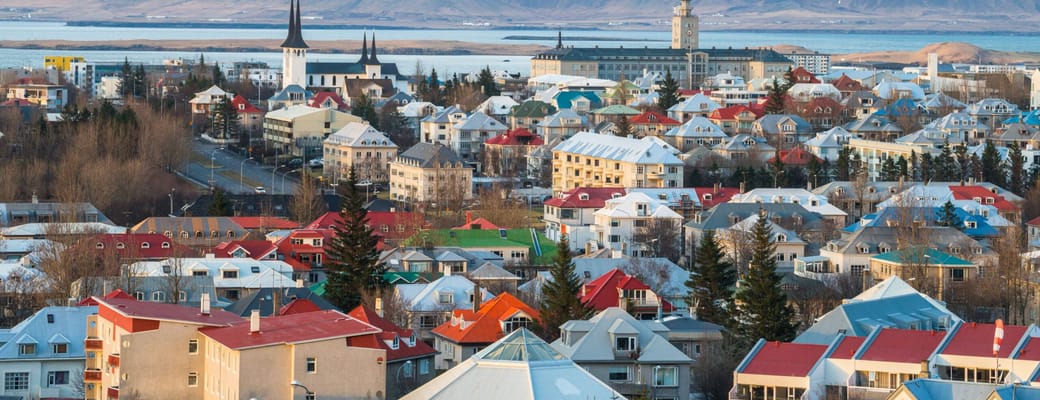 Reykjaviks farverige hustage med Hallgrímskirkja og sne-dækkede bjerge i baggrunden