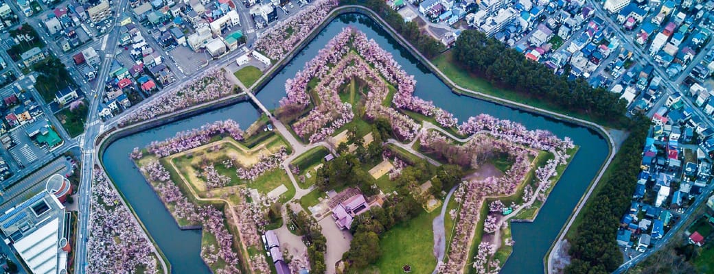 Luftfoto af Goryōkaku stjernef&aelig;stning i Hakodate omgivet af kirseb&aelig;rblomster og moderne byomr&aring;de