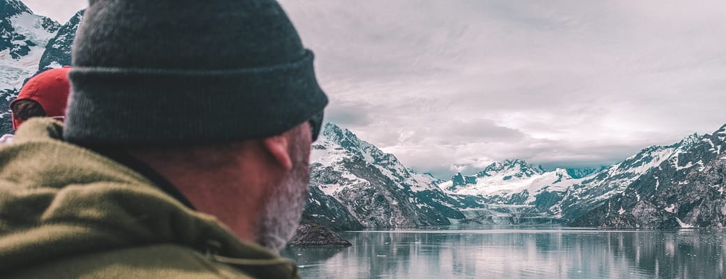 Gæst nyder udsigten over fjord og gletsjere i Inside Passage på luksuskrydstogt i Alaska