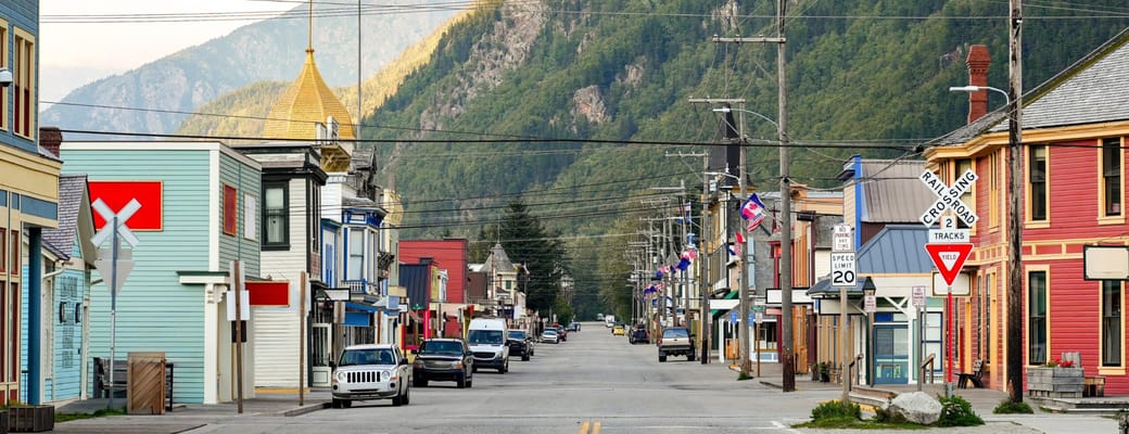 Hovedgaden i historiske guldgraverbyen Skagway med farverige tr&aelig;huse og bjerglandskab i Alaska