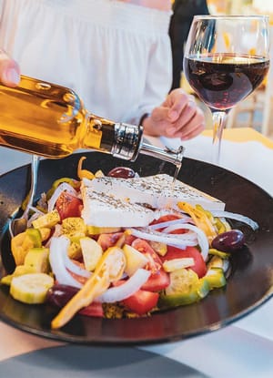 graekenland kvinde haelder olivenolie over salat