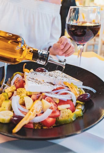 graekenland kvinde haelder olivenolie over salat