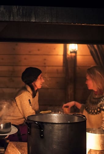 Camp Barentz: i dunkel belysning serverer kvinde suppe for 2 gæster