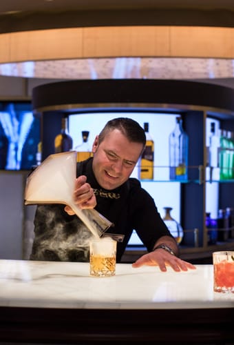 Bartender laver cocktails ved World Class Bar p&aring; Celebrity Solstice med r&oslash;geffekt
