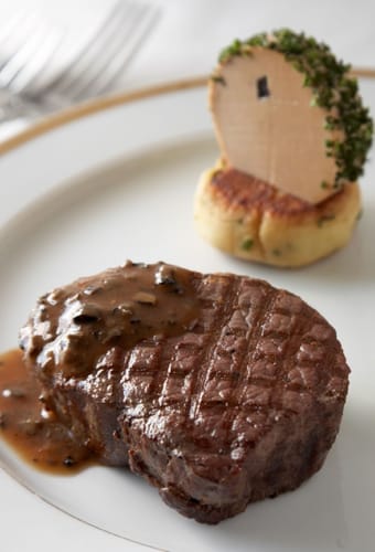 Elegant gourmet bøf serveret på hvid tallerken med asparges og kartoffelkage - fine dining ombord på Celebrity Cruises krydstogtskib