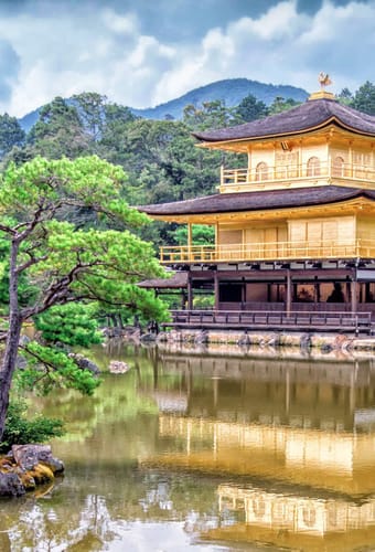 Kinkaku-ji det gyldne tempel i Kyoto omgivet af gr&oslash;nne tr&aelig;er og reflekteret i tempels&oslash;en
