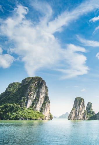 Dramatiske kalkstens&oslash;er i Halong Bay Vietnam med traditionel b&aring;d sejlende i smaragdgr&oslash;nt vand