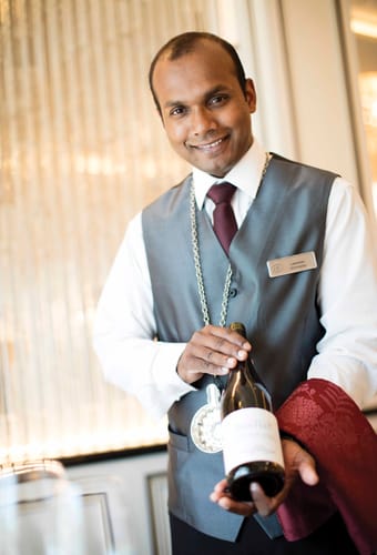 Sommelier i Compass Rose restauranten pr&aelig;senterer vinflaske for g&aelig;sterne