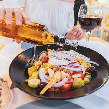graekenland kvinde haelder olivenolie over salat
