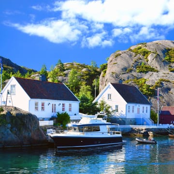 Charmerende hvide træhuse og både i havnen ved Kristiansand i Norge