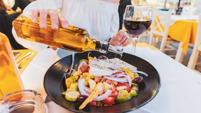 graekenland kvinde haelder olivenolie over salat