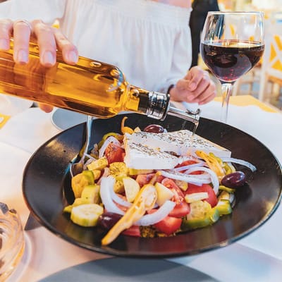 graekenland kvinde haelder olivenolie over salat
