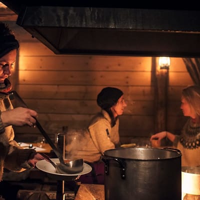 Camp Barentz: i dunkel belysning serverer kvinde suppe for 2 gæster