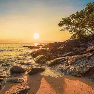 solopgang over strand med klipper ved Khanom thailand