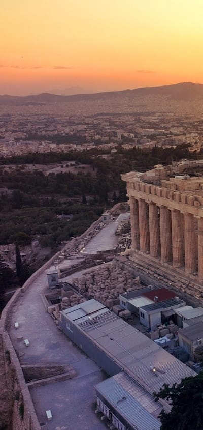 Akropolis og Parthenon i Athen set fra luften i solnedgang med storbyen bredt ud omkring