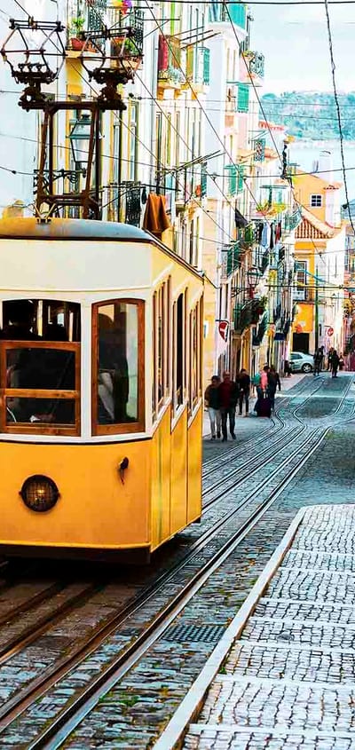 Den historiske Bica-sporvogn k&oslash;rer op ad en stejl brostensgade i Lissabon