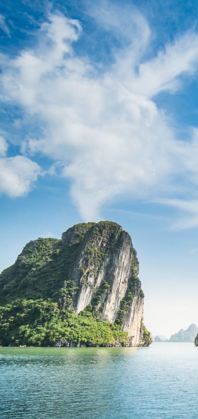 Dramatiske kalkstens&oslash;er i Halong Bay Vietnam med traditionel b&aring;d sejlende i smaragdgr&oslash;nt vand