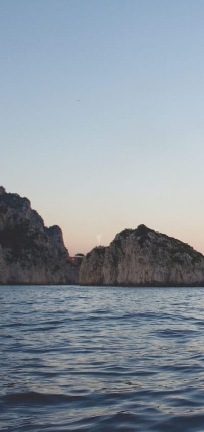 Krydstogtskibet Seven Seas Voyager sejler ved Capri blandt klipper i solnedgang