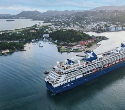 Celebrity Millennium krydstogtskib ved den tropiske &oslash; St. Lucia med gr&oslash;nne bjerge i baggrunden