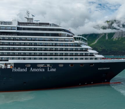 Krydstogtskibet MS Westerdam sejler gennem Yakutat Bay med gr&oslash;nne bjerge og skyer i baggrunden