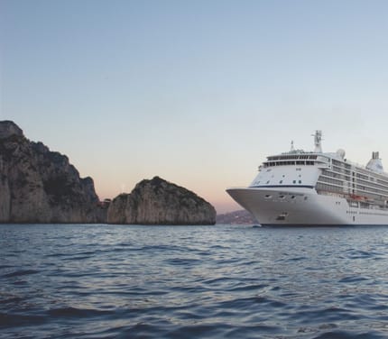 Krydstogtskibet Seven Seas Voyager sejler ved Capri blandt klipper i solnedgang