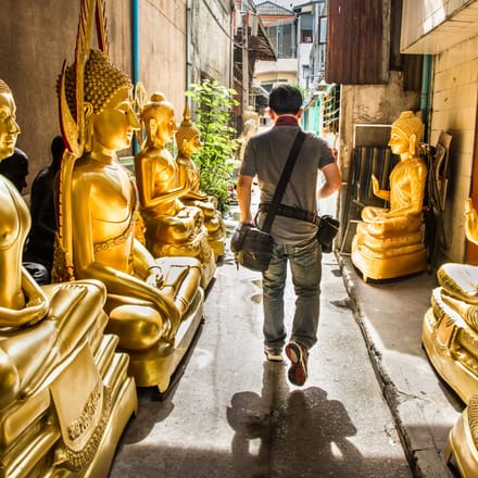 en tourist på gåtur blandt gyldne buddhaer