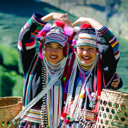 to smilende unge akha kvinder i traditionel kl&aelig;dedragt p&aring; gr&oslash;n bjergside chiang rai nordthailand