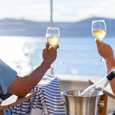 Par nyder champagne i liggestole p&aring; d&aelig;kket med havudsigt ombord p&aring; Holland America Line krydstogt