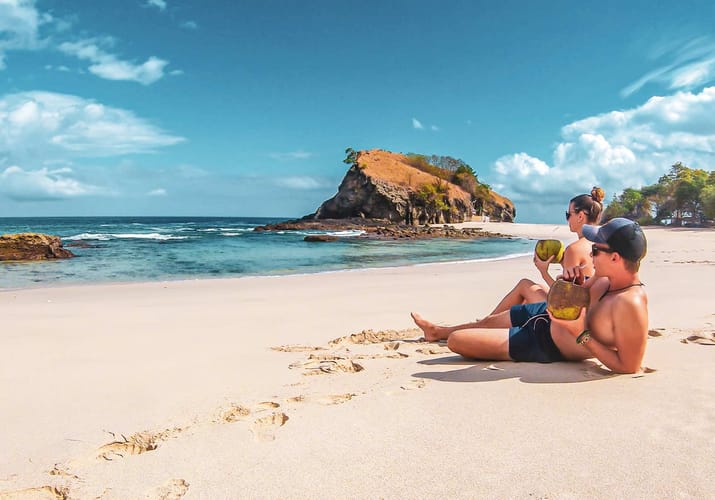 Indonesien flores koka strand par drikker kokosmaelk strand på