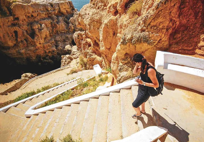 Turist går på trappe ved Algarvekysten i Portugal