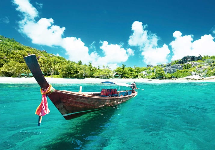 longtail boat i turkisbl&aring;t vand ved strand p&aring; paradis&oslash; i thailand