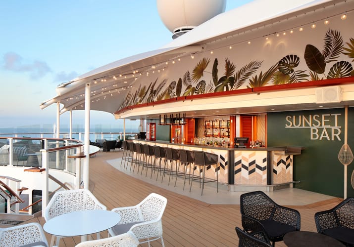 Sunset Bar p&aring; Celebrity cruise skibets &oslash;verste d&aelig;k med tropisk palmeblade-dekoration, udend&oslash;rs barstemning og havudsigt